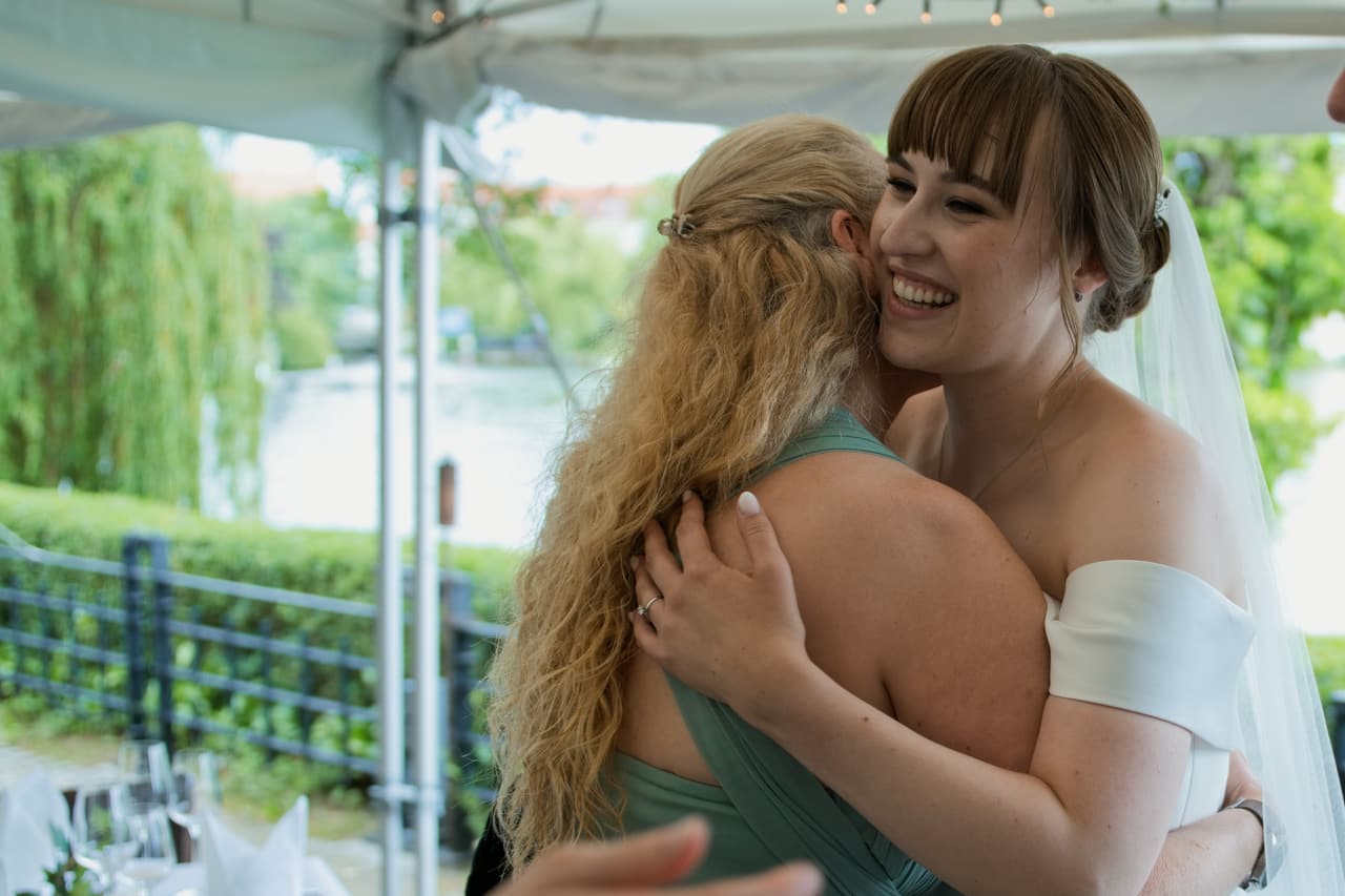 Freundin umarmt die Braut bei der Gratulation am Schlosscafé Köpenick