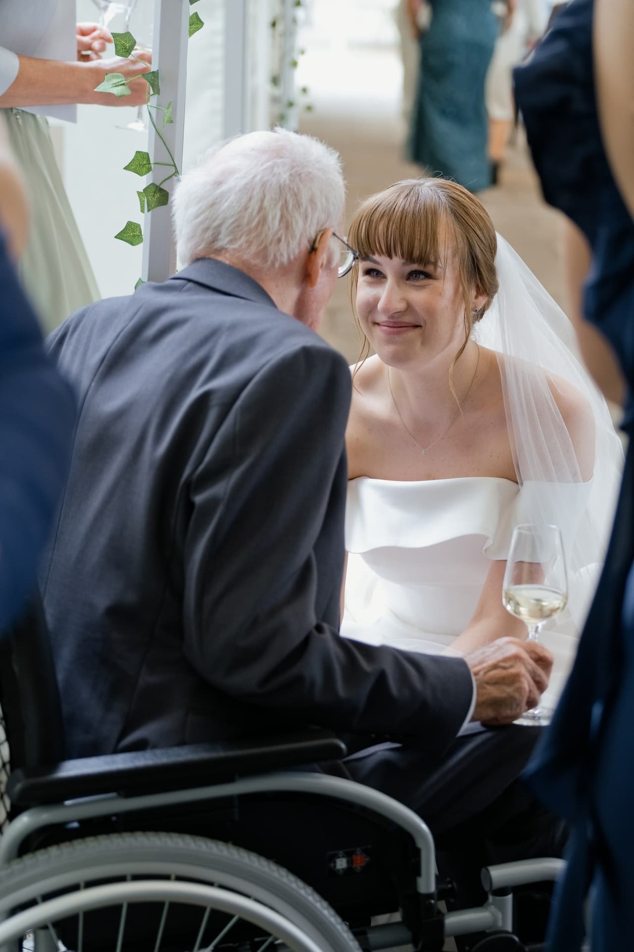 Braut lacht mit ihrem Großvater im Rollstuhl bei der Gratulation