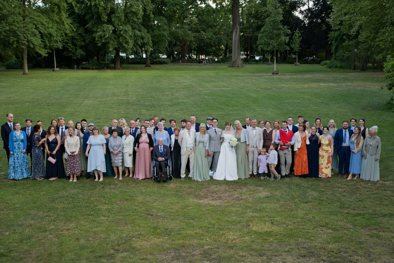 Gruppenfoto aller Hochzeitsgäste auf der Wiese im Schlosspark Köpenick