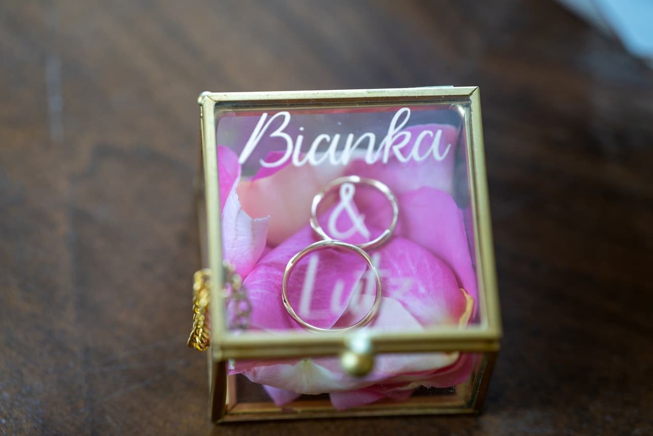 Ringkästchen mit den Namen Bianka & Lutz und den Eheringen auf Rosenblättern