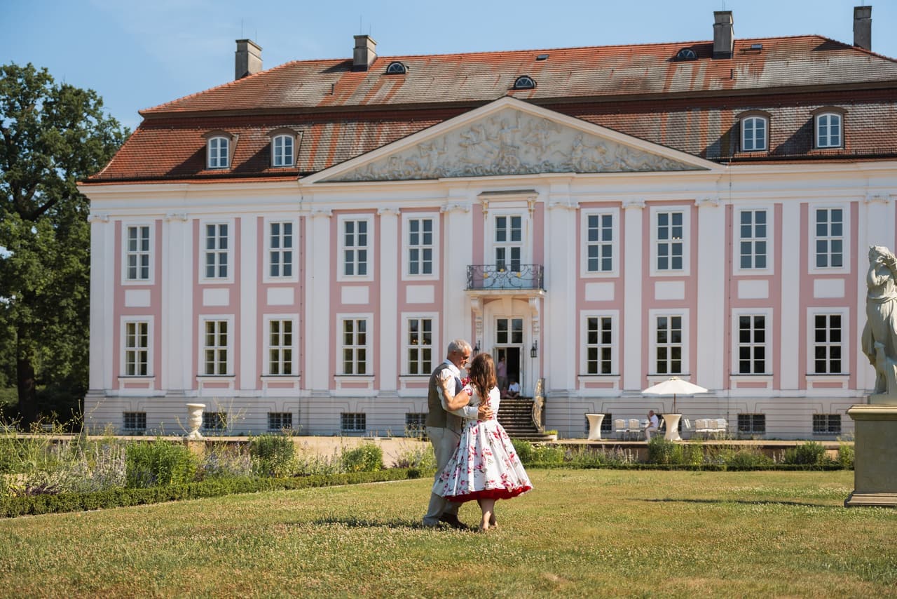 Brautpaar tanzt auf der Wiese vor Schloss Friedrichsfelde