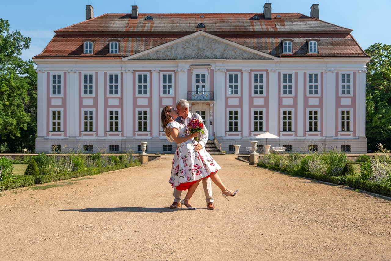 Bräutigam lässt die Braut vor der Fassade von Schloss Friedrichsfelde nach hinten fallen