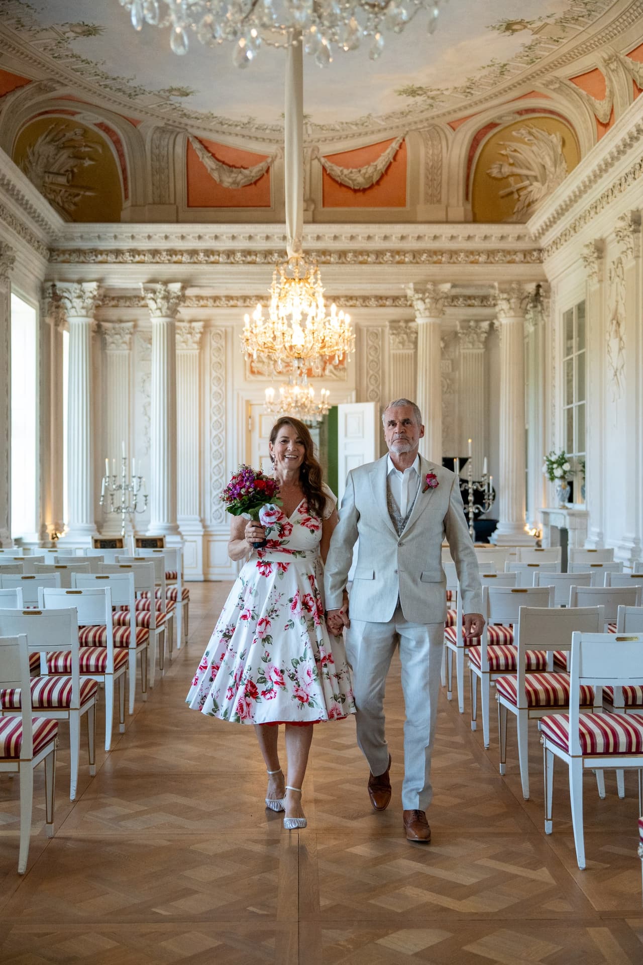 Brautpaar geht Hand in Hand durch den leeren Festsaal von Schloss Friedrichsfelde