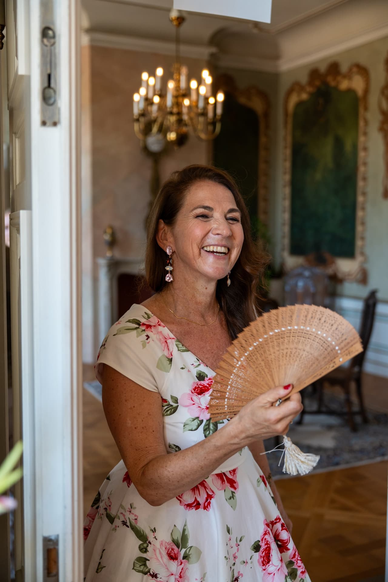 Braut mit Fächer lacht in einem Salon des Schlosses
