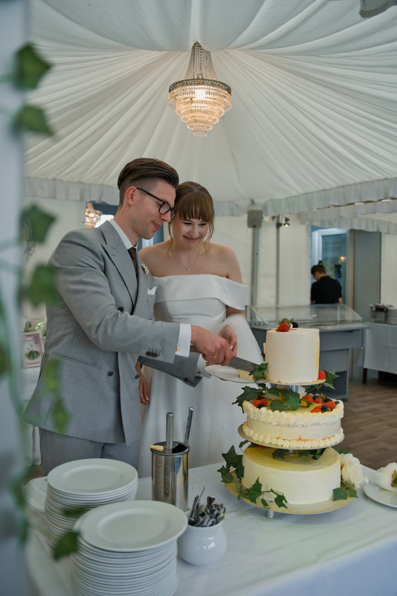 Brautpaar schneidet die Hochzeitstorte im Festzelt mit Kronleuchter an