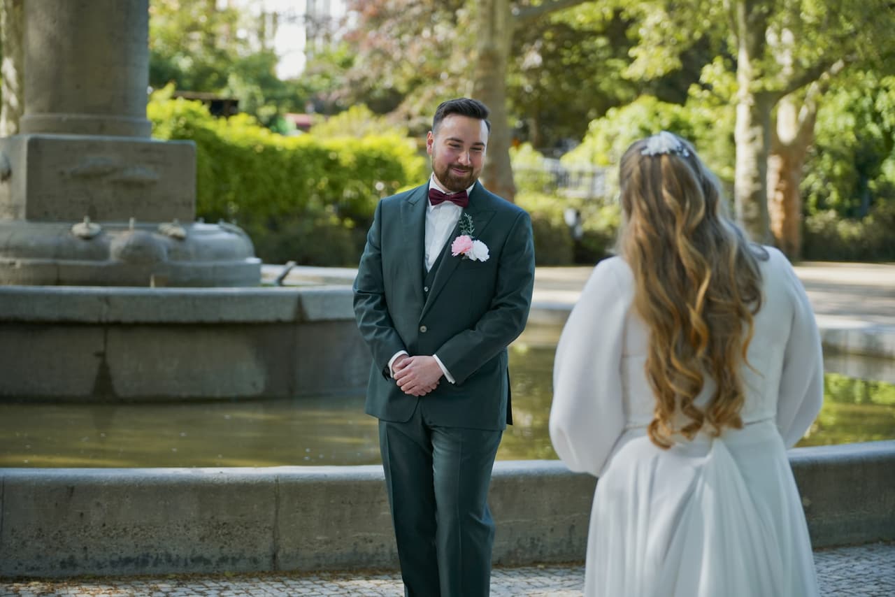 Bräutigam sieht seine Braut beim First Look am Springbrunnen zum ersten Mal