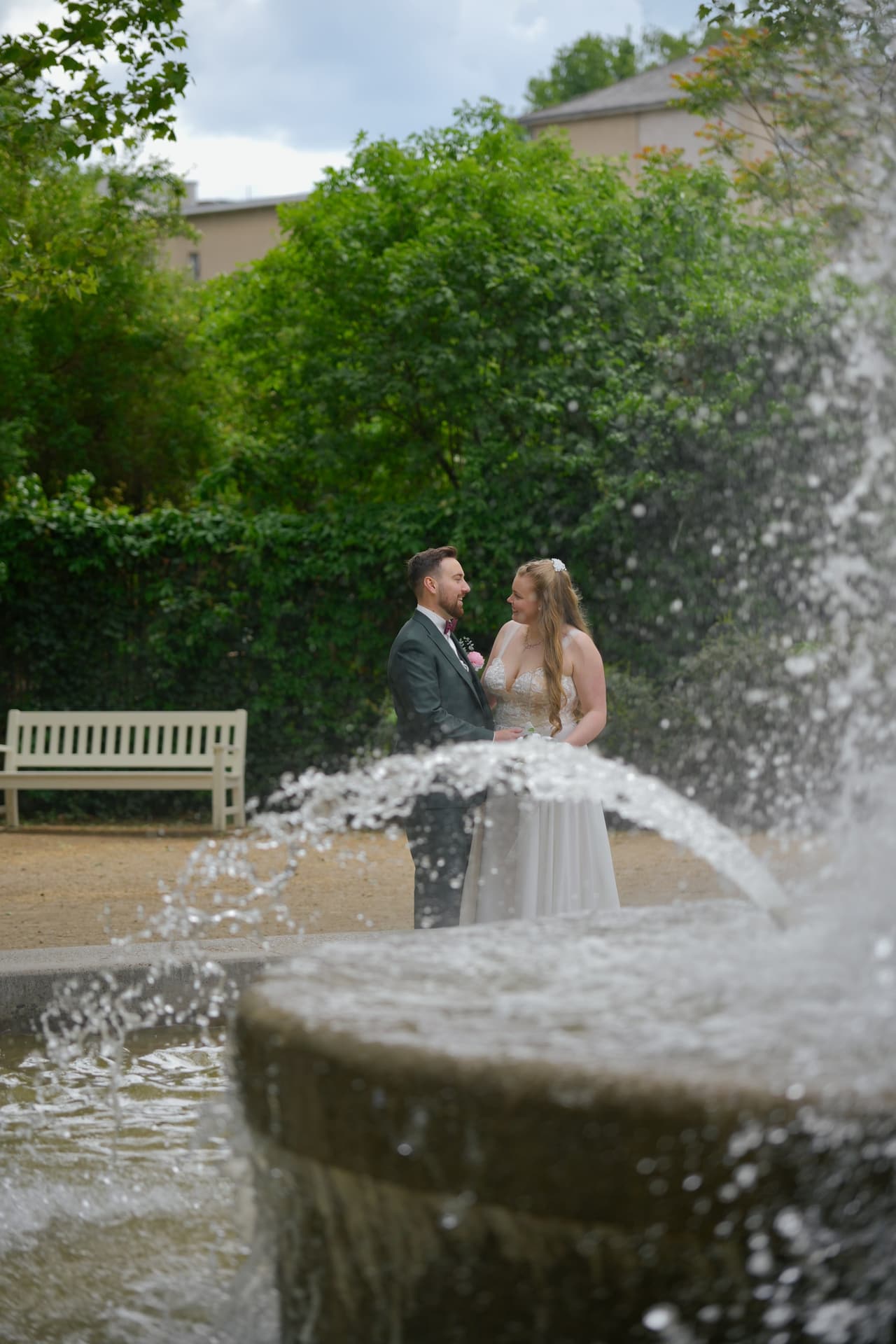 Brautpaar hinter einer Wasserfontäne im Park – Hochzeitsfotografin Berlin