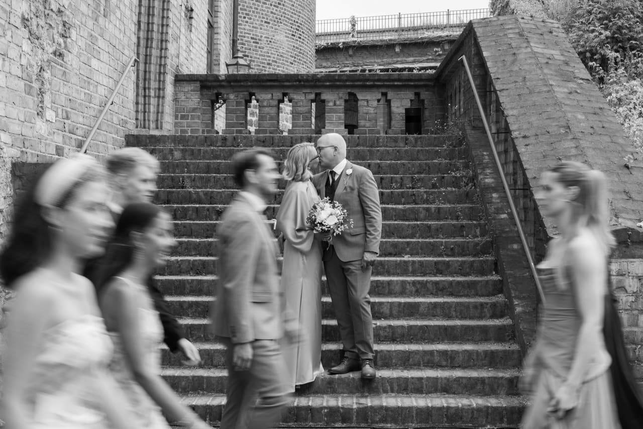 Schwarz-Weiß-Foto: Brautpaar auf der Treppe der Zitadelle Spandau, die Gäste ziehen vorbei