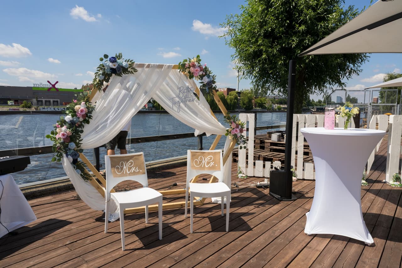 Freie Trauung an der White Spreelounge Berlin, Traubogen und Bestuhlung auf der Terrasse am Wasser, Hochzeitsfotografin Berlin begleitet die