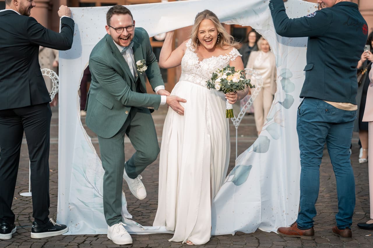 Hochzeit im Standesamt Dortmund, Brautpaar lacht beim Auszug aus dem Standesamt unter dem Schleier